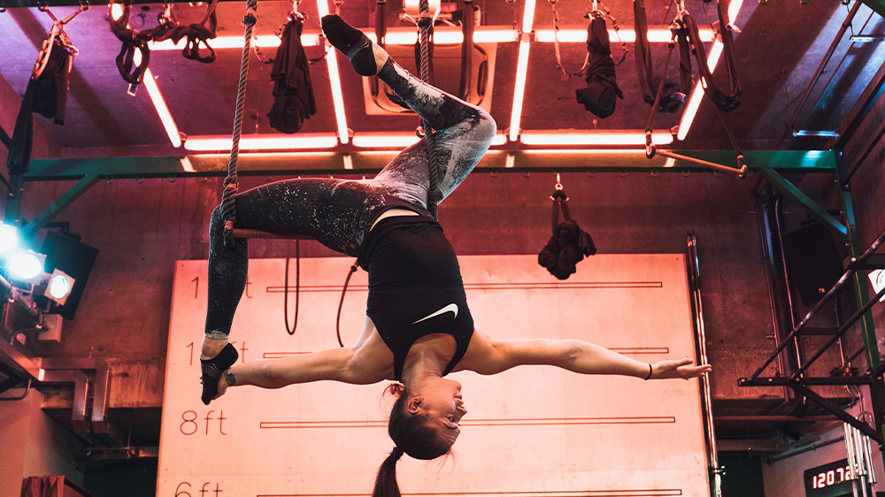 trapeze - woman hangs from a trapeze in an aerial studio