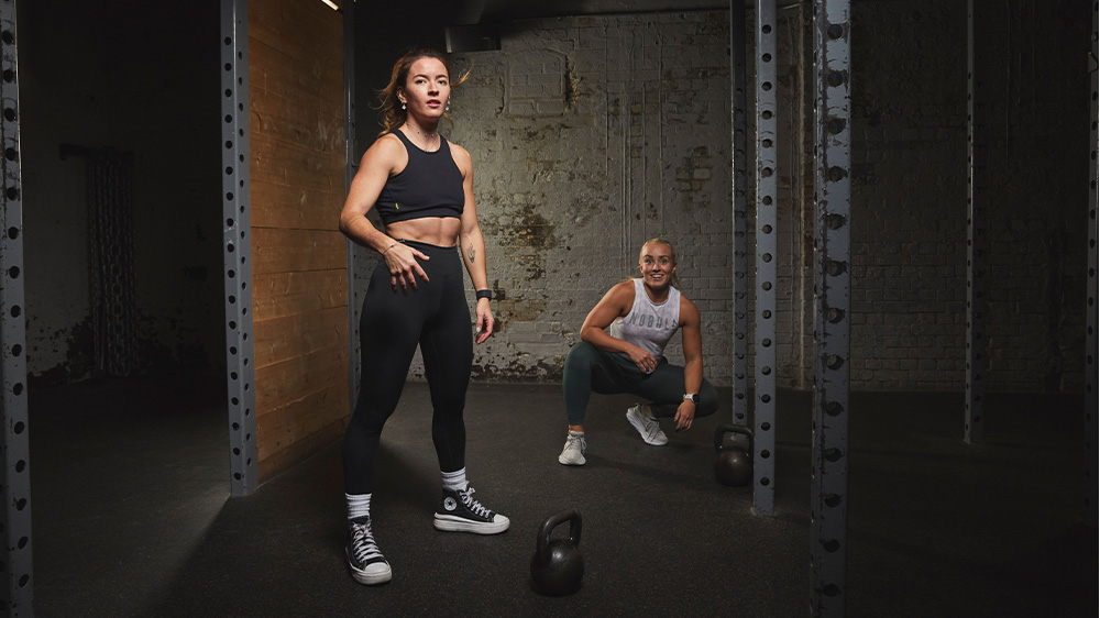 WOD squad END - two women in sportswear stand in a rig